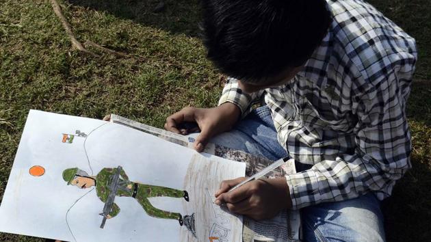 A boy doing some finishing touches to his painting of a soldier who fought for the nation during the 26/11 attacks. (Ravindra Joshi/HT PHOTO)