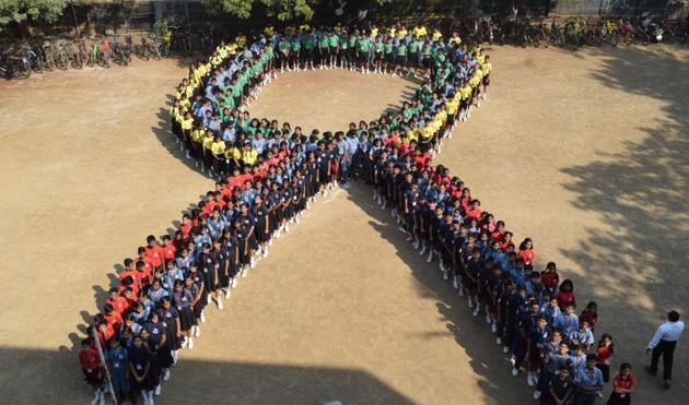 Students assemble in the shape of a ‘ribbon’ on the eve of World AIDS Day in Thane.(Praful Gangurde)