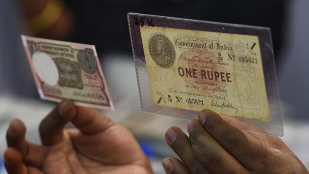 Numismatist Ramesh K. Velunde holds a new Indian One Rupee (L) currency note and an original 100 year-old Indian One Rupee currency note on its 100th anniversary in Mumbai, Maharashtra on November 30, 2017. (Indranil Mukherjee / AFP)