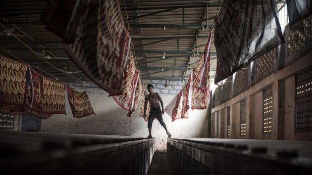 A worker at a sari printing facility skips between troughs in Jetpur, Gujarat. (Satish Bate / HT Photo)