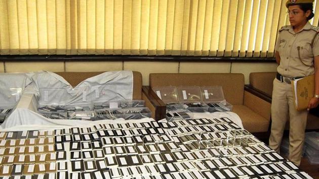 A Delhi Police officer stands next stolen phones recovered after the arrest of a gang of phone snatchers. (HT File) A Delhi Police officer stands next stolen phones recovered after the arrest of a gang of phone snatchers. (HT File)