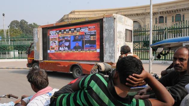 Pedestrians watching live updates of UP Civic polls result on a giant TV screen installed in front of the Vidhan Sabha in Lucknow on December 1.(Subhankar Chakraborty/HT PHOTO)