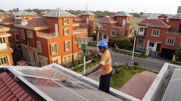 A worker cleans solar panels at a solar housing complex near Kolkata. For curbing the environmental impact of buildings, electrical demand reduction needs to be supported by electricity generation from green sources.(AFP file)