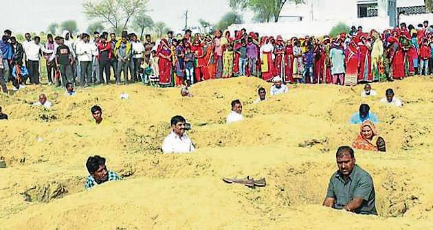 Villagers in Rajasthan’s Jhunjunu sit in 2ft deep pits for three hours on Monday as ‘token protest’ against the local municipal council’s plan to set up a waste treatment plant near the village. (HT Photo.) Villagers in Rajasthan’s Jhunjunu sit in 2ft deep pits for three hours on Monday as ‘token protest’ against the local municipal council’s plan to set up a waste treatment plant near the village. (HT Photo.)