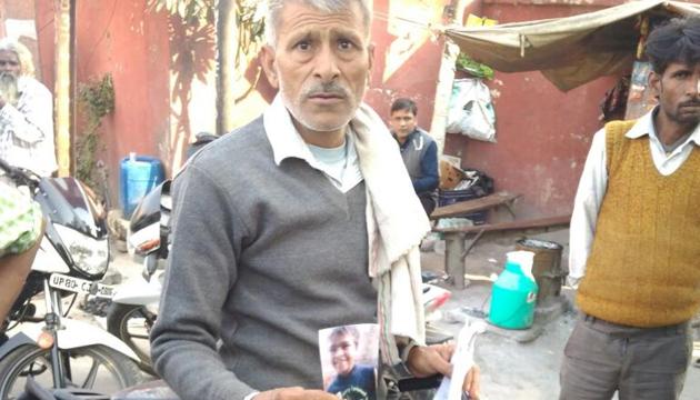 Satish Chandra with a picture of his missing son. The Hathras police have intensified its search after a social activist alerted the police with a tweet.(HT Photo)