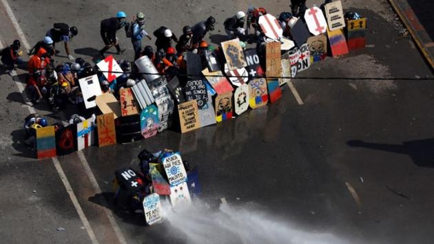 Demonstrators take cover during riots at a march to the state ombudsman's office in Caracas, Venezuela on May 29, 2017. Slogans that read “Maduro, murderer!” and “Maduro, dictator!” began appearing on roads and walls around the country. Though the majority of protesters were peaceful, youths wearing masks and brandishing homemade Viking-style shields started turning up at the front of rallies to taunt security forces. (Carlos Garcia Rawlins / REUTERS) Demonstrators take cover during riots at a march to the state ombudsman's office in Caracas, Venezuela on May 29, 2017. Slogans that read “Maduro, murderer!” and “Maduro, dictator!” began appearing on roads and walls around the country. Though the majority of protesters were peaceful, youths wearing masks and brandishing homemade Viking-style shields started turning up at the front of rallies to taunt security forces. (Carlos Garcia Rawlins / REUTERS)
