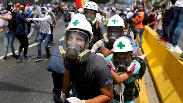 Volunteer members of a primary care response team, huddle together during clashes with security forces at a rally in Caracas, Venezuela on April 26, 2017. Amid raging protests Venezuelans grew accustomed to navigating around barricades and burning streets as they tried to get to school and work. Some days, the country virtually shut down. (Carlos Garcia Rawlins / REUTERS) Volunteer members of a primary care response team, huddle together during clashes with security forces at a rally in Caracas, Venezuela on April 26, 2017. Amid raging protests Venezuelans grew accustomed to navigating around barricades and burning streets as they tried to get to school and work. Some days, the country virtually shut down. (Carlos Garcia Rawlins / REUTERS)