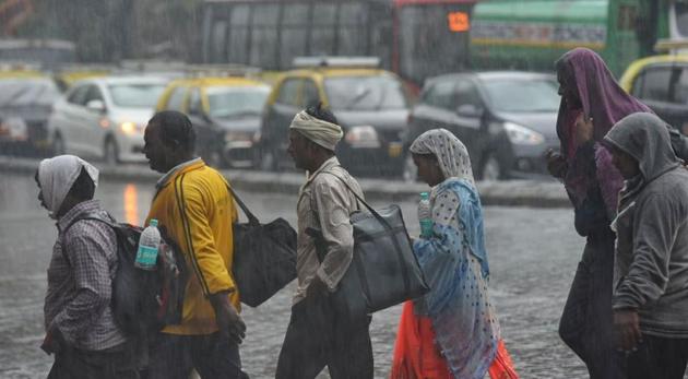 People walk through rain and traffic at Dadar on Tuesday morning. (Pratik Chorge)