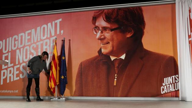 A woman arranges flags in front of a backdrop of ousted Catalan President Carles Puigdemont before a press conference by former Catalan cabinet members Jordi Turull and Josep Rull who were released from jail on bail in Barcelona. (Reuters Photo) A woman arranges flags in front of a backdrop of ousted Catalan President Carles Puigdemont before a press conference by former Catalan cabinet members Jordi Turull and Josep Rull who were released from jail on bail in Barcelona. (Reuters Photo)