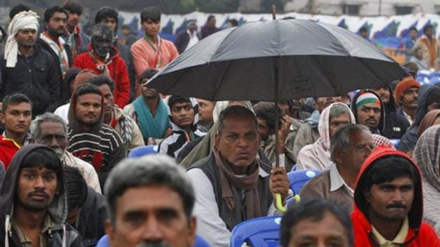 A Congress supporter holds an umbrella to protect from rain during an election rally at Dhrangadhra in Surendranagar district of Gujarat on Tuesday. (AP) A Congress supporter holds an umbrella to protect from rain during an election rally at Dhrangadhra in Surendranagar district of Gujarat on Tuesday. (AP)