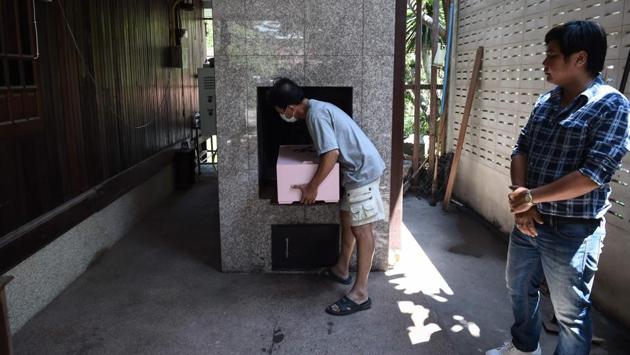 An undertaker places a coffin inside a crematorium in Bangkok. While it makes for a good business -- starting prices are around 3,000 baht (around $91) and the most extravagant services cost up to 100,000 baht -- the monk says the funerals have brought people closer to religion. (Lillian Suwanrumpha / AFP)