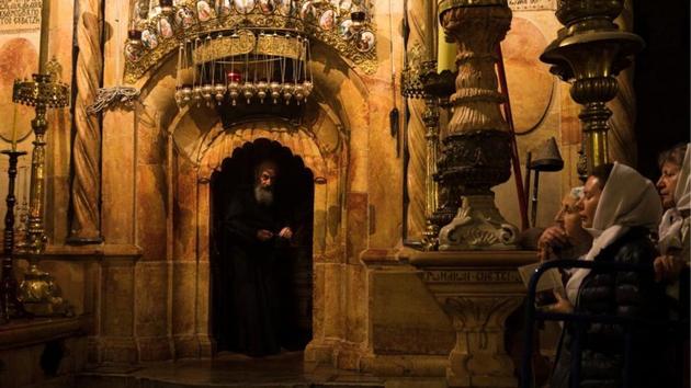 Worshippers stand nearby as a priest peers out from the Edicule, the burial place housing the purported tomb of Jesus, at the Church of the Holy Sepulchre. The Greek Orthodox, Armenian and Roman Catholic denominations share custody of the church, where tensions often run high over control of its various sectors. (Ronen Zvulun / REUTERS) Worshippers stand nearby as a priest peers out from the Edicule, the burial place housing the purported tomb of Jesus, at the Church of the Holy Sepulchre. The Greek Orthodox, Armenian and Roman Catholic denominations share custody of the church, where tensions often run high over control of its various sectors. (Ronen Zvulun / REUTERS)