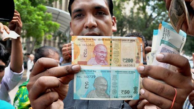 A man shows new currency notes of Rs 200 and Rs 50 outside the Reserve Bank of India in New Delhi.(PTI File Photo)