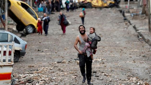 A man screams in terror cradling his daughter to safety, dodging fire in an ISIS-controlled part of Mosul towards Iraqi Special Forces soldiers, in March 2017. An awkward coalition of the army, Shi’ite Muslim paramilitaries and Kurdish Peshmerga driven by political and sectarian differences, chased an elusive, fanatical enemy, mustering rare unity to end a reign of terror in Iraq’s second city Mosul, seat of the ultra-hardline insurgents’ “caliphate”. (Goran Tomasevic / REUTERS)