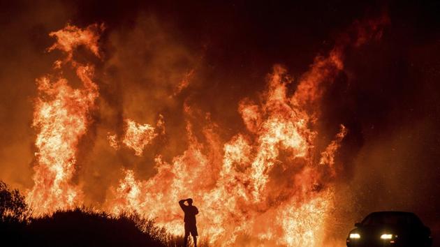 A motorists on Highway 101 watches flames from the Thomas fire leap above the roadway north of Ventura, California. (AP) A motorists on Highway 101 watches flames from the Thomas fire leap above the roadway north of Ventura, California. (AP)