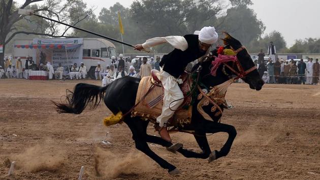 A Pakistani rider charges across a course holding a lance to pick up pegs at a tent-pegging competition during an annual festival at the village of Kot Fateh Khan in Attock, Punjab province. Festooned with garlands and colourful bridles, turbaned riders mounted on horseback gallop, aiming at tiny wooden blocks keeping alive a centuries-old tradition of tent-pegging in Pakistan. (Aamir Qureshi / AFP) A Pakistani rider charges across a course holding a lance to pick up pegs at a tent-pegging competition during an annual festival at the village of Kot Fateh Khan in Attock, Punjab province. Festooned with garlands and colourful bridles, turbaned riders mounted on horseback gallop, aiming at tiny wooden blocks keeping alive a centuries-old tradition of tent-pegging in Pakistan. (Aamir Qureshi / AFP)
