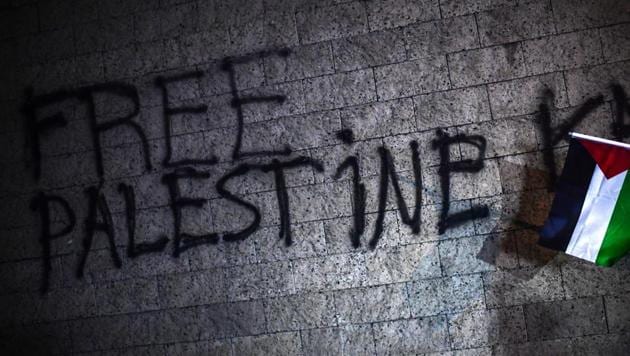 A protester waves a Palestinian flag near the words "Free Palestine" spray-painted onto a wall of the US consulate during a demonstration against the US and Israel in front of the US consulate in Istanbul on December 6, 2017.(AFP Photo)