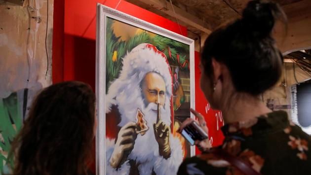 Visitors look at a painting depicting Russian president Vladimir Putin as Father Frost, the Russian equivalent of Santa Claus, at the exhibition. These aren’t his latest series of publicity photos, but rather artwork at a new Moscow exhibition focussed on Russia’s leader. (Maxim Shemetov / REUTERS)