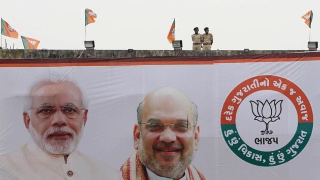 Policemen keep vigil from terrace of a building with a huge hoarding featuring Prime Minister Narendra Modi and Amit Shah during an election campaign rally at Surendranagar in Gujarat.(AP Photo)
