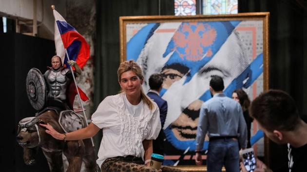 A woman poses for a picture with a sculpture depicting Russian president Vladimir Putin riding a bear at the exhibition in UMAM museum in Moscow. The exhibition features around 30 paintings and sculptures of the Russian leader in a variety of different styles, all of which were made by Russian artists. (Maxim Shemetov / REUTERS)