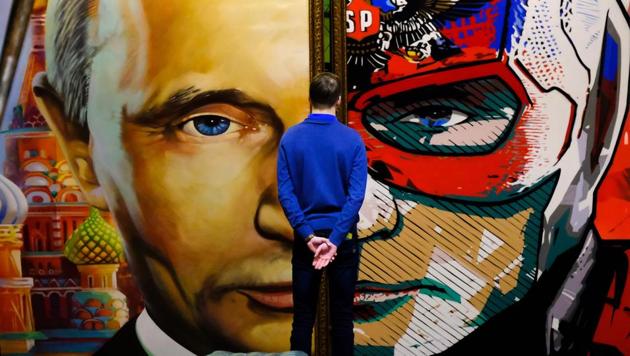 Part Russian president, part superhero --a man looks at a diptych of the Russian leader at the "SUPERPUTIN" exhibition at UMAM museum in Moscow on December 06, 2017. (Yuri Kadobnov / AFP)