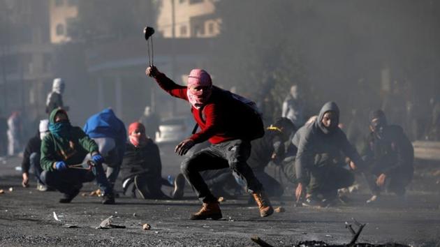 A Palestinian protester uses a sling to hurl stones towards Israeli troops during clashes as Palestinians call for a "day of rage" in response to President Donald Trump's recognition of Jerusalem as Israel's capital, near the Jewish settlement of Beit El, near the West Bank city of Ramallah, December 9, 2017(REUTERS)