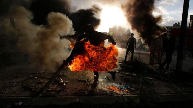 A Palestinian protester runs after catching fire during clashes with Israeli troops at a protest against US President Donald Trump's decision to recognize Jerusalem as the capital of Israel, near the Jewish settlement of Beit El, near the West Bank city of Ramallah on December 7, 2017. (Abbas Momani / AFP) 