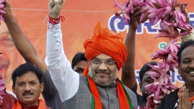 BJP members felicitate party's National President Amit Shah with 150 lotus garland during his election campaign rally for assembly election in Kheda on Saturday. (PTI) BJP members felicitate party's National President Amit Shah with 150 lotus garland during his election campaign rally for assembly election in Kheda on Saturday. (PTI)