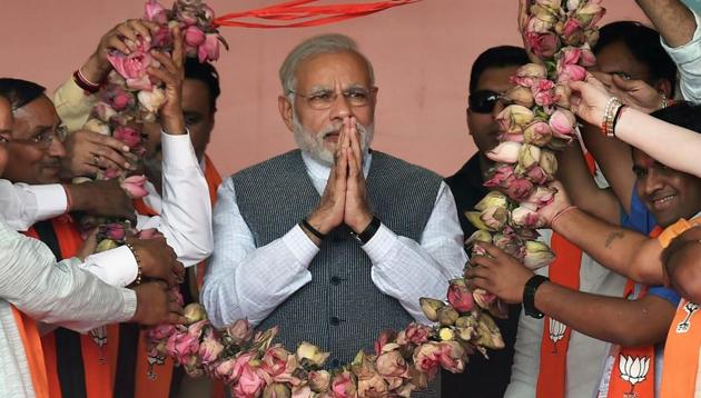 Prime Minister Narendra Modi being presented a lotus-garland by the BJP workers during an election campaign rally in Sanand on Sunday.(PTI)