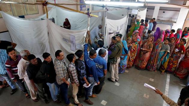 People stand in queues to cast their votes inside a polling booth during the first phase of Gujarat assembly election in Limbdi town of Surendranagar district, December 9, 2017.(REUTERS)