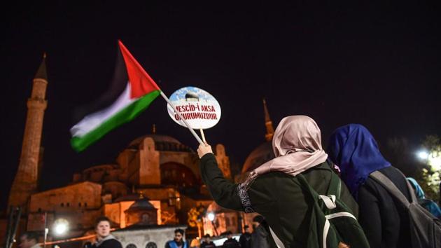 Pro-Palestine protesters hold a Palestine flag and a placard that reads "Al Quds is our honor" (Al Quds is the Arabic name for the city of Jerusalem, literally meaning "The Holy One") during a demonstration against the US and Israel on December 9, 2017 in front of Hagia Sophia museum in Istanbul.(AFP Photo)