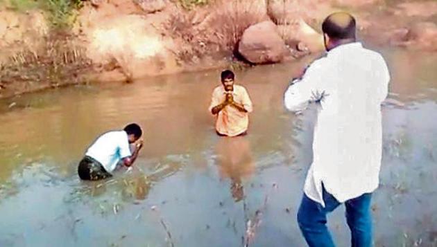 video showing BJP leader M Bharat Reddy (in white) forcing the two men to take a dip in a muddy pond has gone viral. (Screengrab) video showing BJP leader M Bharat Reddy (in white) forcing the two men to take a dip in a muddy pond has gone viral. (Screengrab)