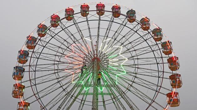 Men repair tubelights on a ferris wheel. The ‘Urs’ festival is an annual celebration in the memory of Hazrat Makhdum Ali Mahimi, a 14th century Sufi scholar.  (Shashi S Kashyap/HT PHOTO) 