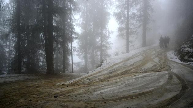 People walk through a snow glazed road after fresh snowfall at Kufri, Shimla. Tourists from the plains have begun to descend on to popular tourist sites like Manali and Kufri. (Deepak Sansta / HT Photo) 