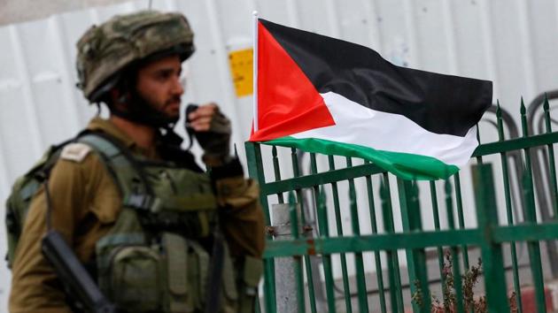 A member of the Israeli security forces stands next to a Palestinian flag during clashes with Palestinian protesters following a demonstration in the West Bank town of Hebron on December 13, 2017, as protests continue in the region amid anger over US President Donald Trump's recognition of Jerusalem as its capital. (AFP) A member of the Israeli security forces stands next to a Palestinian flag during clashes with Palestinian protesters following a demonstration in the West Bank town of Hebron on December 13, 2017, as protests continue in the region amid anger over US President Donald Trump's recognition of Jerusalem as its capital. (AFP)