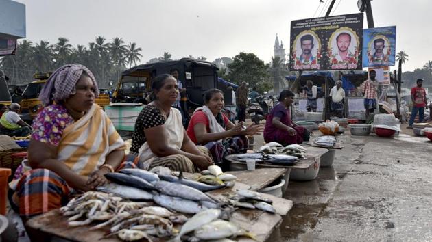 Photographs of fishermen who died are displayed (top right) as women sell fish at the Vizhinjam fishing harbour in Thiruvananthapuram, on Wednesday. (AP) Photographs of fishermen who died are displayed (top right) as women sell fish at the Vizhinjam fishing harbour in Thiruvananthapuram, on Wednesday. (AP)