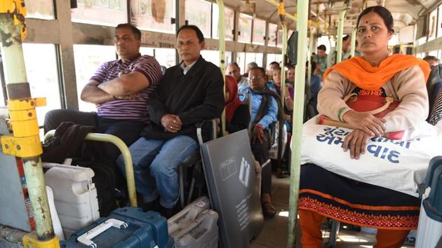 Officials travel on a bus with Electronic Voting Machines and Voter Verifiable Paper Audit Trail (VVPAT) ahead of the second phase of Gujarat Vidhan Sabha elections in Ahmedabad on Wednesday.(AFP Photo)