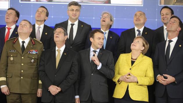 French President Emmanuel Macron, front center, speaks with German Chancellor Angela Merkel, front second right, as they look up at a drone flying above their heads during a group photo at an EU summit at the Europa building in Brussels on Thursday, Dec. 14, 2017. (AP Photo) French President Emmanuel Macron, front center, speaks with German Chancellor Angela Merkel, front second right, as they look up at a drone flying above their heads during a group photo at an EU summit at the Europa building in Brussels on Thursday, Dec. 14, 2017. (AP Photo)