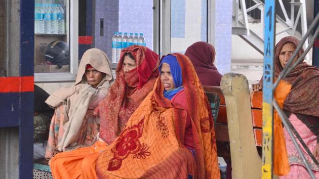 Wrapped in warm clothes, people wait at the railway station on a cold winter day in Amritsar on Saturday. (Sameer Sehgal/HT)