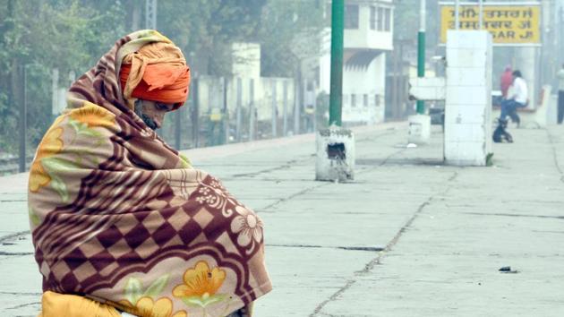 A man wraps a blanket around him while waiting at the Amritsar railway station on a cold winter morning in Amritsar on Saturday. (Sameer Sehgal/HT)