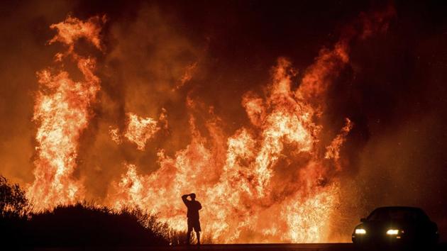 A motorist on Highway 101 watches flames leap above the roadway north of Ventura. The blazes forced many schools to close for days, shut roads and drove hundreds of thousands from their homes. (Noah Berger / AP) A motorist on Highway 101 watches flames leap above the roadway north of Ventura. The blazes forced many schools to close for days, shut roads and drove hundreds of thousands from their homes. (Noah Berger / AP)