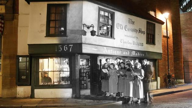 Old Curiosity Shop seen in 1956 and 2014 at Christmas time. In 1956, students of King’s College are seen singing Christmas carols outside the Old Curiosity Shop while the present photo depicts a stark contrasts of a more subdued storefront. (Peter Macdiarmid/Getty Images) Old Curiosity Shop seen in 1956 and 2014 at Christmas time. In 1956, students of King’s College are seen singing Christmas carols outside the Old Curiosity Shop while the present photo depicts a stark contrasts of a more subdued storefront. (Peter Macdiarmid/Getty Images)