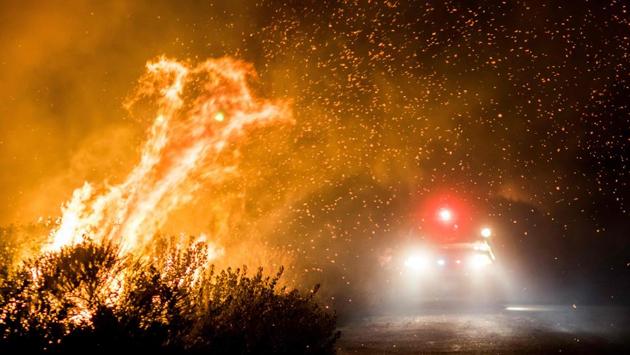The Thomas Fire burns past the 101 Highway towards the Pacific Coast, threatening multi-million dollar mansions with blazes that have already forced more than 200,000 people to flee. The fight to contain the fire so far is estimated at $97 million. (Kyle Grillot / AFP) The Thomas Fire burns past the 101 Highway towards the Pacific Coast, threatening multi-million dollar mansions with blazes that have already forced more than 200,000 people to flee. The fight to contain the fire so far is estimated at $97 million. (Kyle Grillot / AFP)