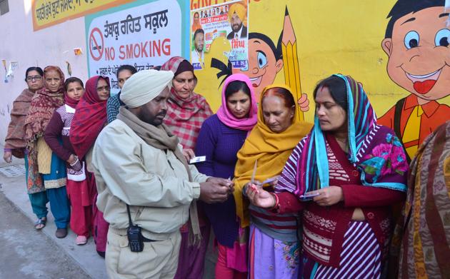 A police personnel checking the identity cards of voters outside a polling station in Amritsar. (Sameer Sehgal )