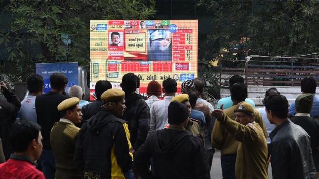 Constituents view a vote tally on a projection screen in Ahmedabad on December 18, 2017. The Election Commission of India is announcing the results on eciresults.nic.in. According to figures released by the Election Commission, an average 68.41% polling was recorded in the elections. The BJP was leading in 99 seats and the Congress in 77. (Satish Shankar Bate / HT Photo)