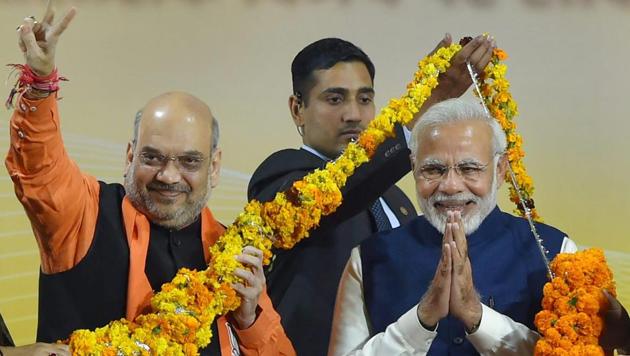 BJP president Amit Shah and Prime Minister Narendra Modi greet supporters after the party's win in Gujarat and Himachal Pradesh assembly elections, at the party headquarters in New Delhi on Monday.(PTI Photo)