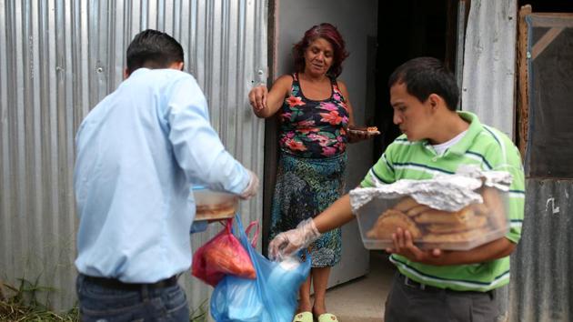 Renderos (L) and Joseph Ramirez of the Huellas de Esperanza ministry, sell their produce to local residents in their neighbourhood. Gomez says they aim to open a bigger bakery and one day run their own store to compete against Pizza Hut. (Jose Cabezas / REUTERS) 