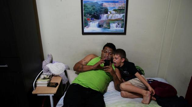 Raul Valladares plays with his son at home in the Dina neighbourhood. He is part of a crew busy making the store a reality and works on the construction site near the bakery. Once known as “The Shadow,” he is undergoing a process to remove tattoos from his face and arms. This has brought death threats from former gang associates because removing gang insignia is punishable by death. (Jose Cabezas / REUTERS) 