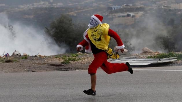Santa Claus makes a getaway during clashes with Israeli troops at a protest against US President Donald Trump's decision to recognize Jerusalem as the capital of Israel, near the West Bank city of Ramallah. (Mohamad TorokmanREUTERS)