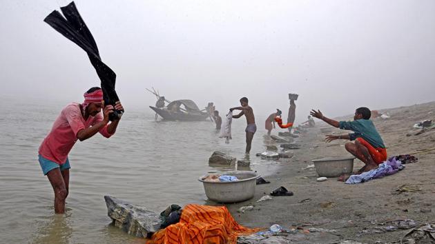 People wash clothes on the banks of the river Brahmaputra on a foggy winter morning in Guwahati, on December 4, 2017.(Reuters)